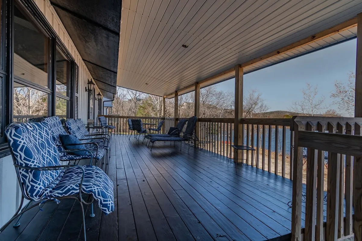 An exterior deck featuring comfortable seating arrangements and a scenic view over the lake. The deck has a secure railing and offers a tranquil setting for relaxing, reading, or socializing while enjoying the waterfront and surrounding nature.